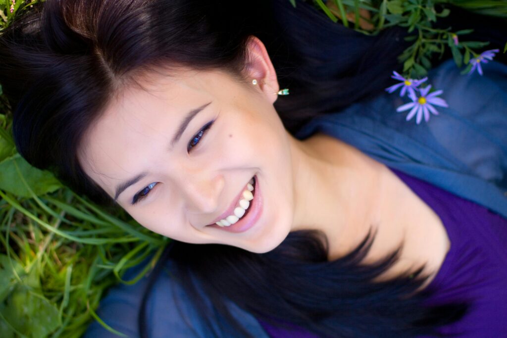 Woman laying down on the grass, looking up into the sky in amazement